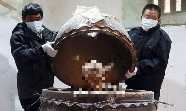 In this photo taken Sunday Jan. 10, 2016, men remove the top of a jar containing the mummified body of revered Buddhist monk Fu Hou in Quanzhou city in southeastern China's Fujian province. The monk, who died in 2012 at the age of 94, was prepared for mummification by his temple to commemorate his devotion to Buddhism. The mummifed remains were then treated and covered in gold leaf, a practice reserved for holy men in some areas with strong Buddhist traditions. (Chinatopix via AP) CHINA OUT
